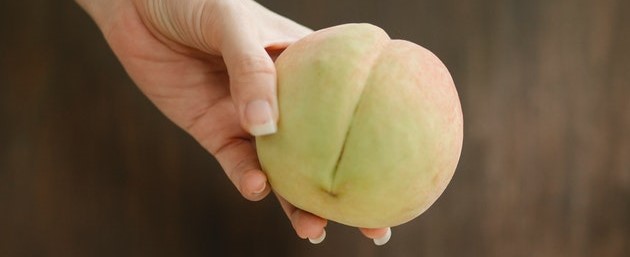 A hand holding a peach